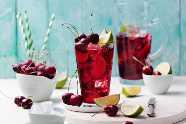 Cherry cola, limeade, lemonade, cocktail in a tall glass on a white, turquoise background